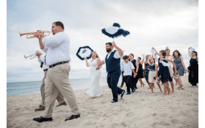 A Seaside Weddings & Events in Emerald Isle, couple and guests celebrate walking on beach following two men