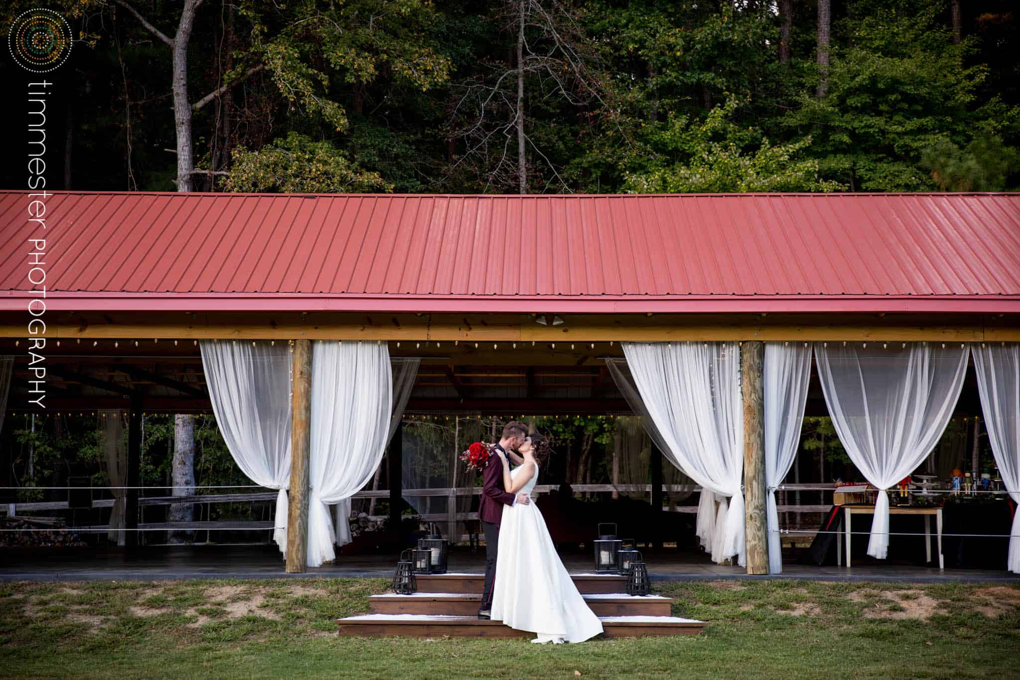 Bride and Groom kissing in front of barn