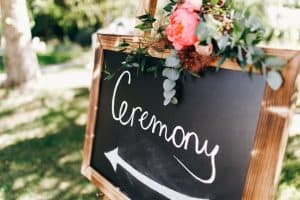 Black board with lettering 'Ceremony' stands on the path in the garden