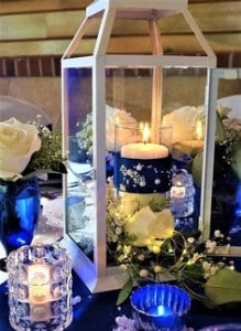 Blue themed center pieces filled with candles, flowers in a clear piece