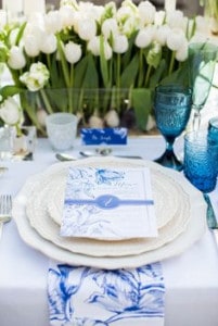 Blue themed table set with blue and white invitation on white plates