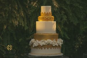 White and Gold Wedding Cake in front of fern wall - Confectionate Cakes - Hall at Landmark Wedding - Charlie and Camellia - Nieto Photography - Forever Bridal Wedding Shows
