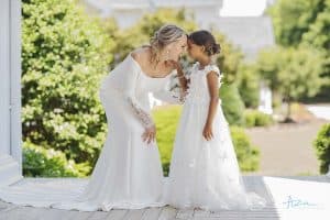 Bride and Flower Girl sharing a moment on sunny porch