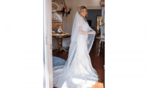 Sinderellas Rockefellas Bridal Boutique bride holding her veil while looking sideways at camera indoors