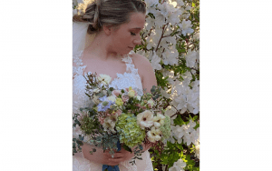 Sinderellas Rockefellas Bridal Boutique bride posing with bouquet surrounded by white florals