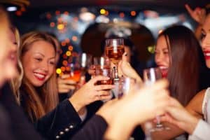 A group of women celebrate with drinks in a limo party bus.