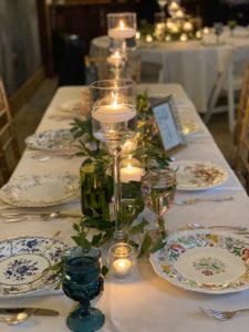 Table set with porcelain plates, candles and greenery.